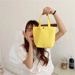 Close-up of yellow canvas lunch bag featuring a sturdy metal snap button closure