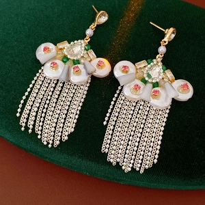Detail of vintage fan-shaped earrings with rhinestones, pearls and delicate metal tassels