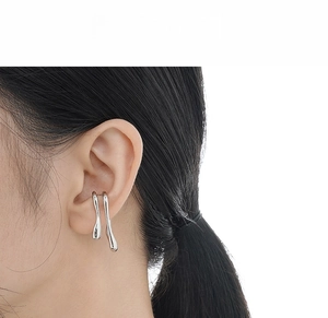 Detail view of irregular liquid metal style S925 sterling silver ear cuffs on a model