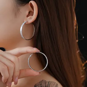 Silver round hoop earrings with textured matte finish shown on model in premium style