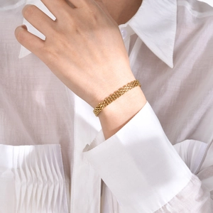 Close-up of golden mesh necklace on model showing intricate woven steel texture