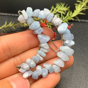 Macro detail of crescent moon hair clip crafted with light blue crystals and silver wire