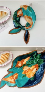 Detail of plissé pleated silk scarf featuring retro floral print and wavy edge finish