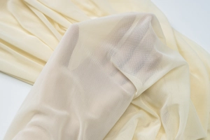 Close-up of light yellow mesh fabric showing breathable texture and sheer material quality