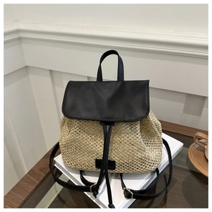Detailed view of the woven straw backpack placed on books with leather flap and buckles