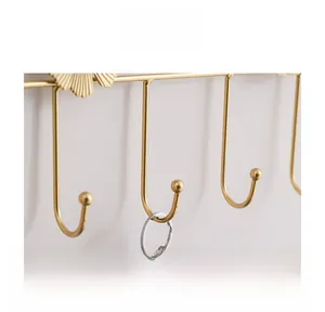 Detail view of golden ginkgo leaf wall hooks with keys hanging on polished metal