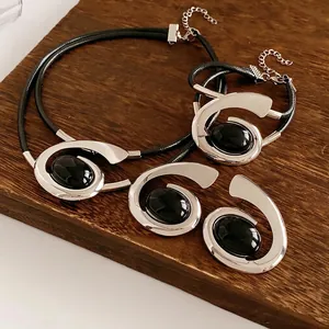 Vintage silver spiral jewelry set with black oval stones on a dark wood background