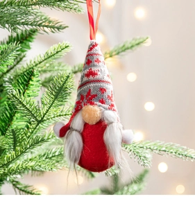 Detailed close-up of a plush gnome hanging on a Christmas tree with warm festive lighting