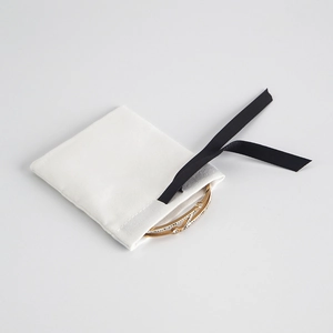 Close-up of golden bracelet with white crystals and drawstring jewelry storage pouch