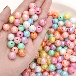 Colorful acrylic craft beads with iridescent finish held in hand for DIY jewelry making