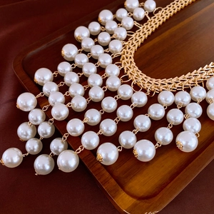 Vue détaillée du collier multicouche en perles et chaîne dorée sur plateau sombre