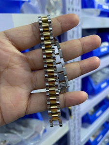 Detail shot of two-tone stainless steel watchband with gold and silver links and clasp