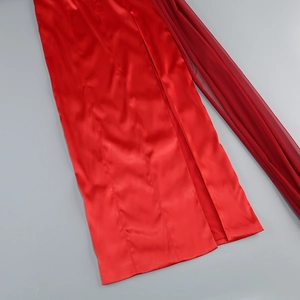 Detailed close-up of the red satin fabric and sheer mesh slit on the evening gown