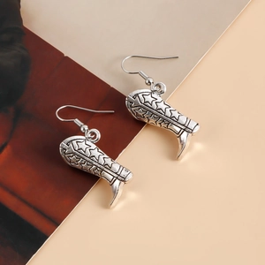 Détail de boucles d'oreilles bottes de cow-boy argentées avec motifs d'étoiles