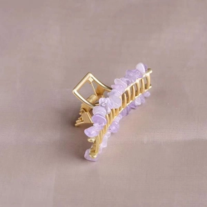 Detailed view of golden alloy hair claw clip featuring natural amethyst crystal fragments