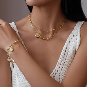 Détail d'un collier doré multicouche avec pendentifs tournesol, étoile de mer et perle