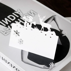 Detail of white laser-cut Christmas place card with snowflake and reindeer patterns
