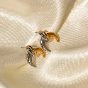 Close-up of two-tone C-hoop earrings in gold and silver finish on beige silk