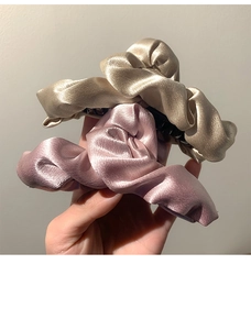 Dettaglio di fermagli per capelli in raso oro champagne e rosa con trama a pieghe