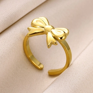 Macro detail of golden bow knot ring on silk background with adjustable open band design