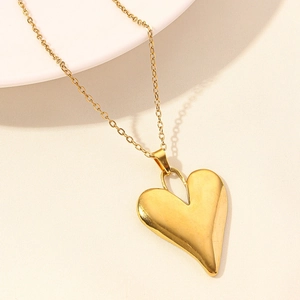 Close-up of polished 18k gold plated heart pendant necklace on textured surface
