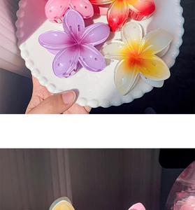 Detail view of colorful resin frangipani flower hair claws in pink, purple and orange hues