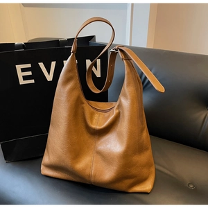 Detail of tan leather hobo bag with vertical stitching and adjustable shoulder strap