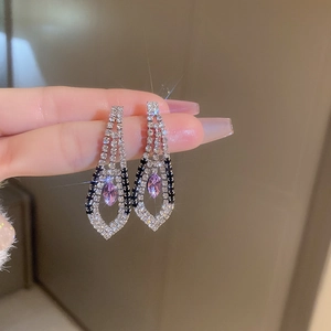 Close-up of geometric drop earrings featuring sparkling purple marquise stones and silver finish