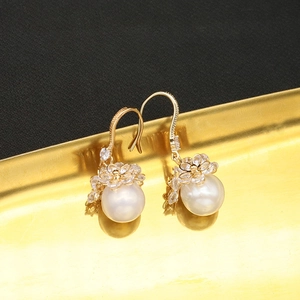 Elegant gold flower pearl earrings with sparkling zircon on a vintage metal display