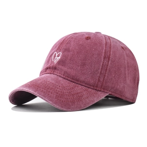 Washed burgundy cotton baseball cap with white heart embroidery in a 45-degree side view