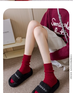 Detail of red compression socks with vertical knit texture worn in a cozy winter setting