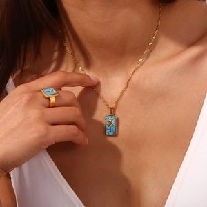 Detail of 18K gold plated necklace and ring set with blue shell and palm tree charm