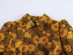Detail view of vintage jacquard fabric featuring gold floral rose prints and black buttons