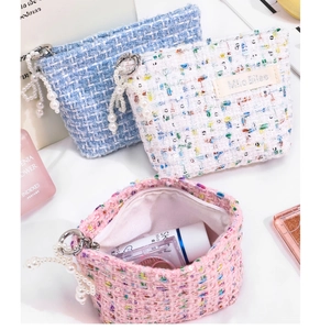 Close-up of elegant tweed storage bags with pearl tassel charms in various colors