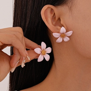 Close-up of a pink floral stud earring with golden stamen on a female model