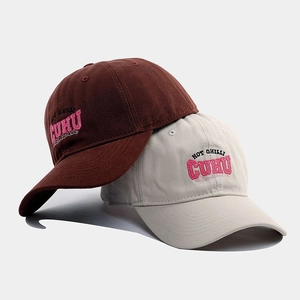 Close-up of embroidered cotton baseball caps in brown and beige with 3D text detail