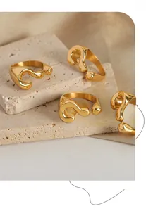 Detailed view of polished gold plated question mark open rings on a marble stone surface