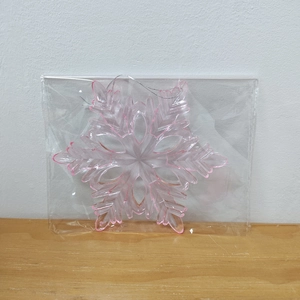 Detail of transparent pink-edged acrylic snowflake ornament with a hanging string