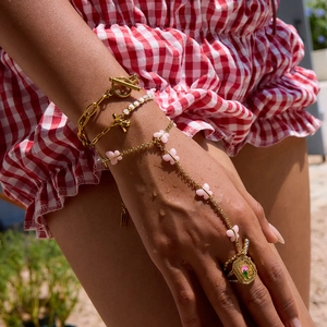 Detail of tropical gold jewelry set with pink butterfly accents and palm tree ring design
