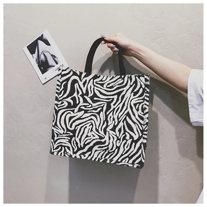 Detail of a zebra print canvas tote bag with black woven handles for daily use
