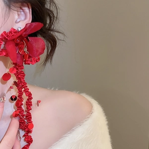 Macro detail of red fabric flower earrings with sparkling sequins and long fringes