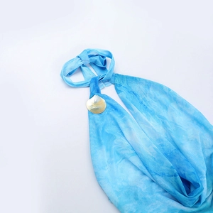 Macro detail of blue tie-dye mesh dress showing shell button and fine fabric texture