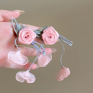 Detail of pink fabric rose earrings with delicate hanging buds and satin finish