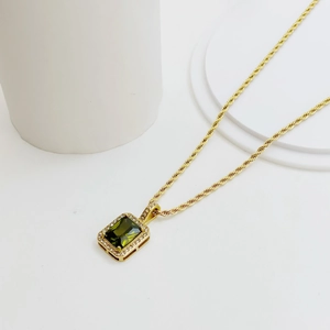 Macro shot of 18K gold twist chain with green rectangular zircon gemstone pendant