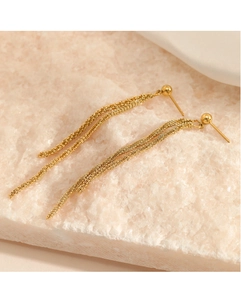 Detail of long gold tassel earrings with fine woven metal chains on white mineral stone
