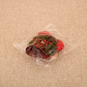 Detail of Christmas iron bell with red berries and pine needles in transparent packaging