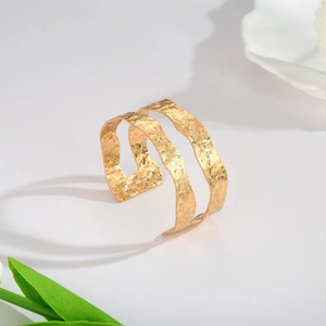 Detail showing the double-layer open gold cuff with hammered texture and polished finish