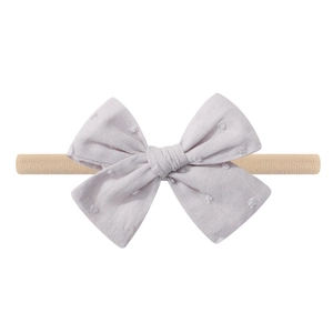 Macro detail of lavender polka dot cotton bow on a beige elastic nylon baby headband