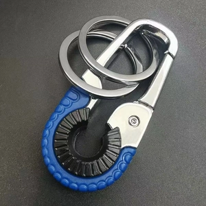 Macro shot of a silver metal car keychain featuring a black bottle opener and blue grip