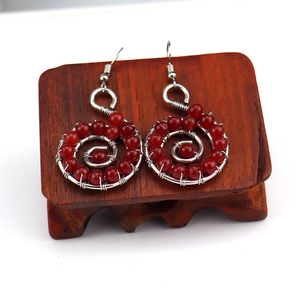 Macro detail of handmade silver wire spiral earrings with red carnelian agate beads
